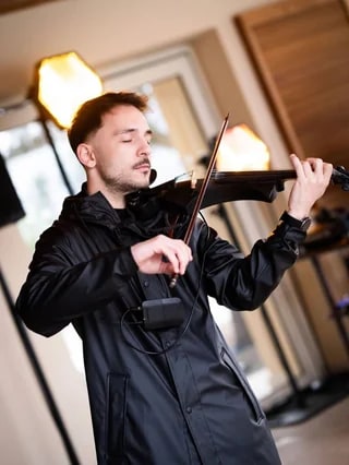 A violinist playing a black violin indoors
