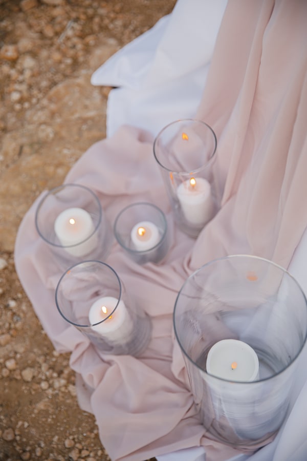 Glass candle holders arranged beside soft pink fabric