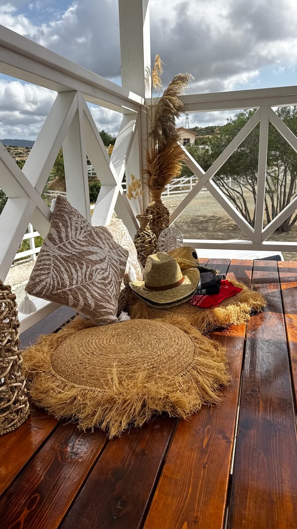 Ranch-inspired cushions, dried grasses and hats on a wooden terrace