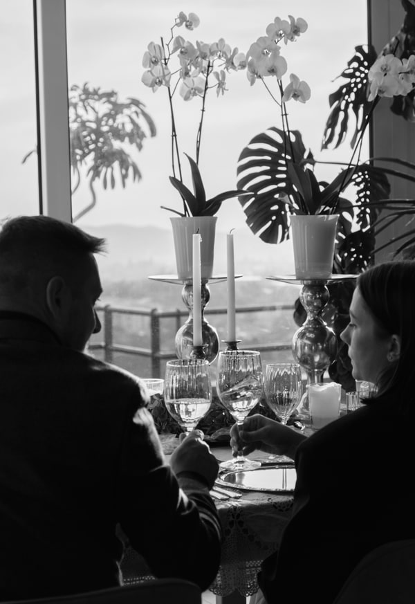 A couple at a candlelit table beside large windows