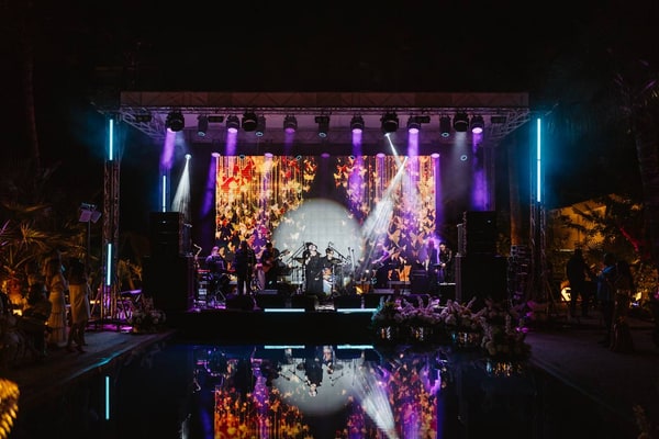 An illuminated stage reflected in the pool at night