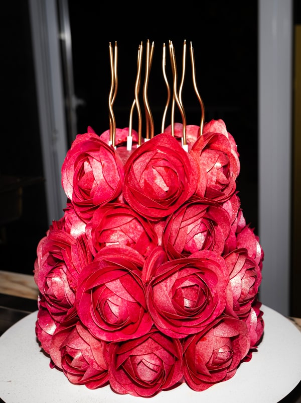 A cake decorated with red icing roses and long candles
