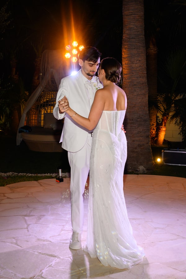 The newlyweds dancing together under evening lights