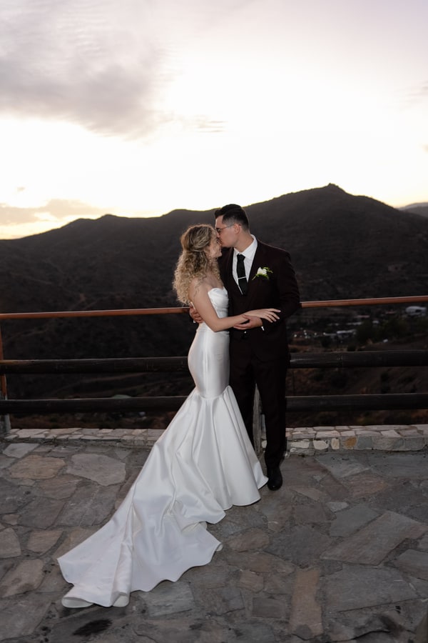 Darya and Andrey sharing a kiss on the terrace as the light fades