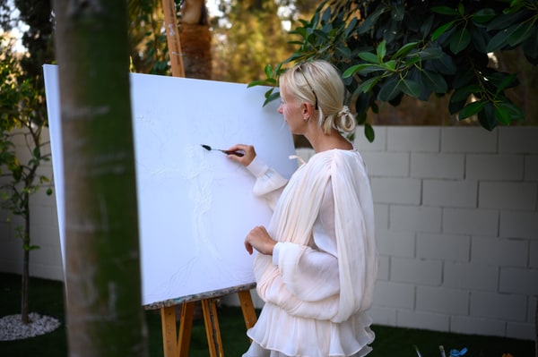 An artist and painting materials beside a garden easel