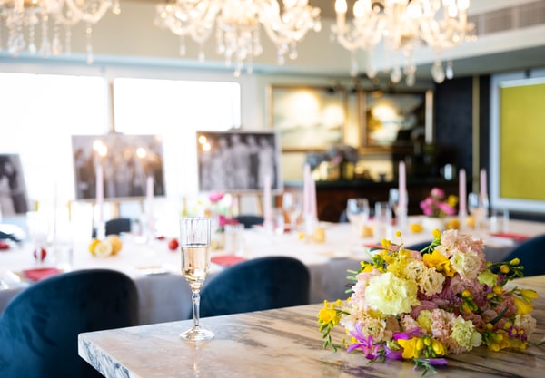 A long table with flowers, pink candles and lemons beneath chandeliers