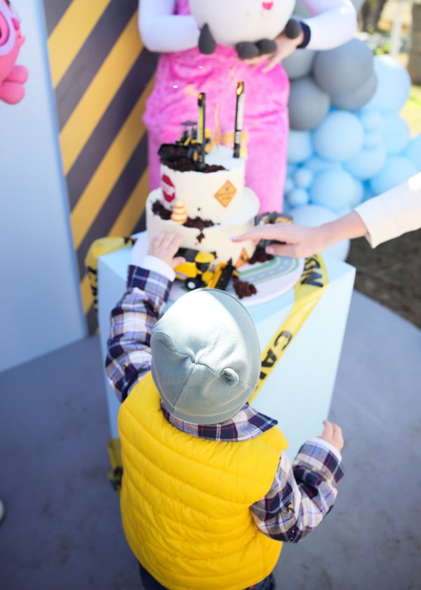 An entertainer presenting the construction-themed birthday cake