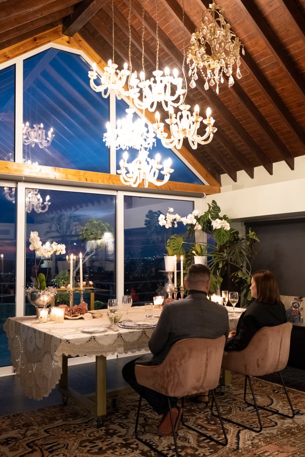 A couple at a candlelit table beside large windows