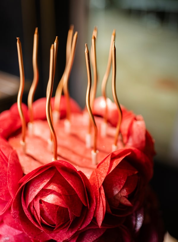 A cake decorated with red icing roses and long candles