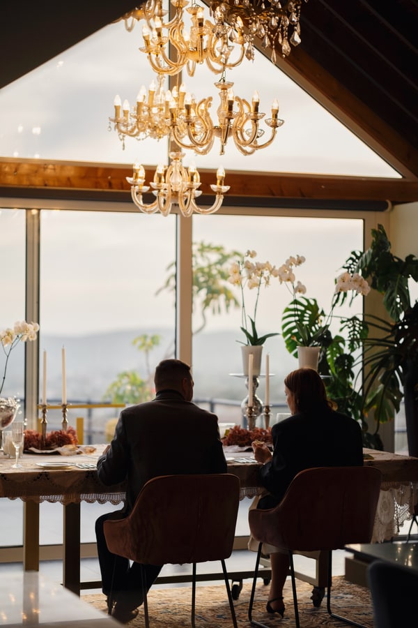 A couple at a candlelit table beside large windows
