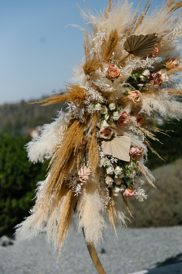 Dried grasses and pale flowers decorating the wedding arch