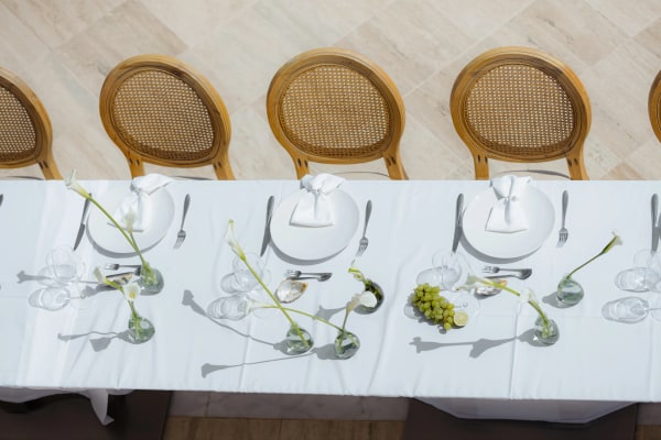 White place settings, glassware and green floral stems along the wedding table