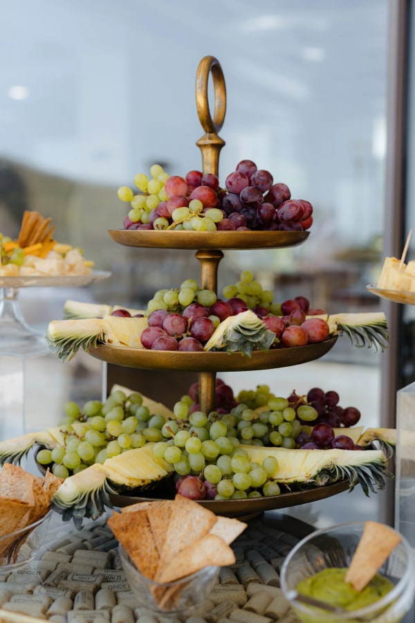 A tiered fruit stand with grapes and pastries in the reception setting