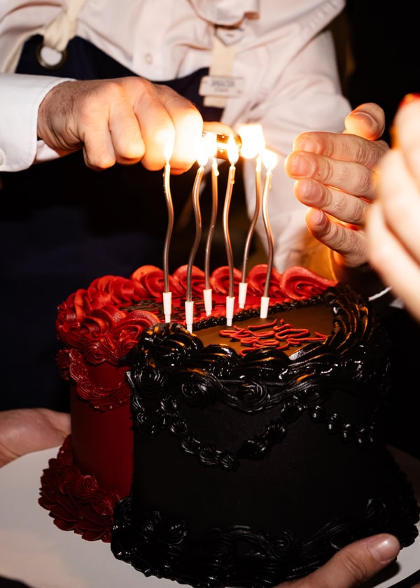 A black and red birthday cake with candles