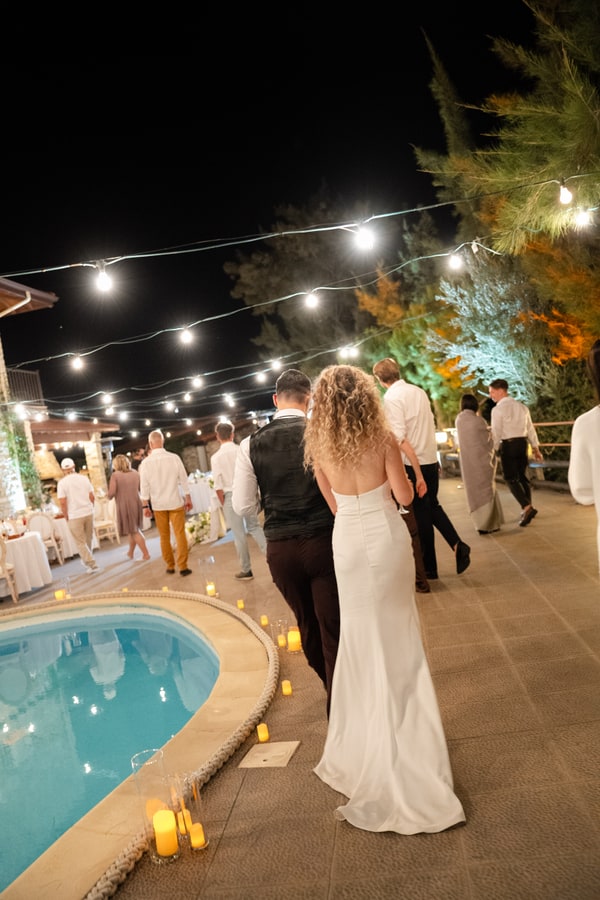 The bride and guests celebrating beside the pool under evening lights