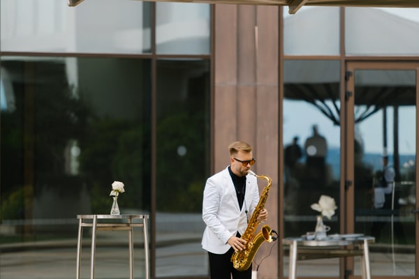 A saxophonist in a white jacket performing outdoors