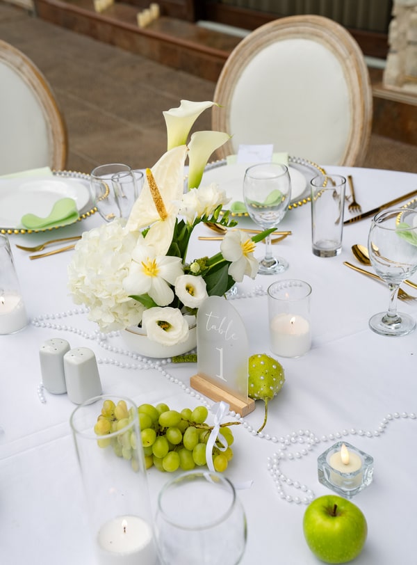 White calla lilies, green pears and glass candle holders in the table styling